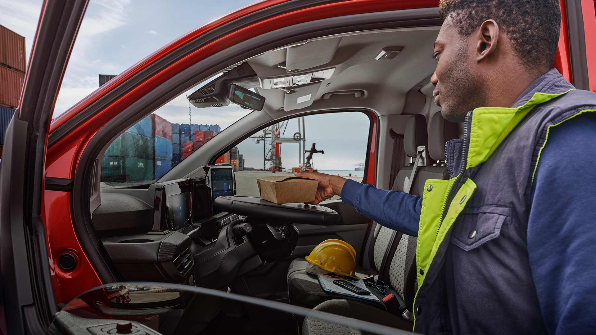 Pessoa a colocar uma encomenda no interior de um Ford Transit Custom vermelho.