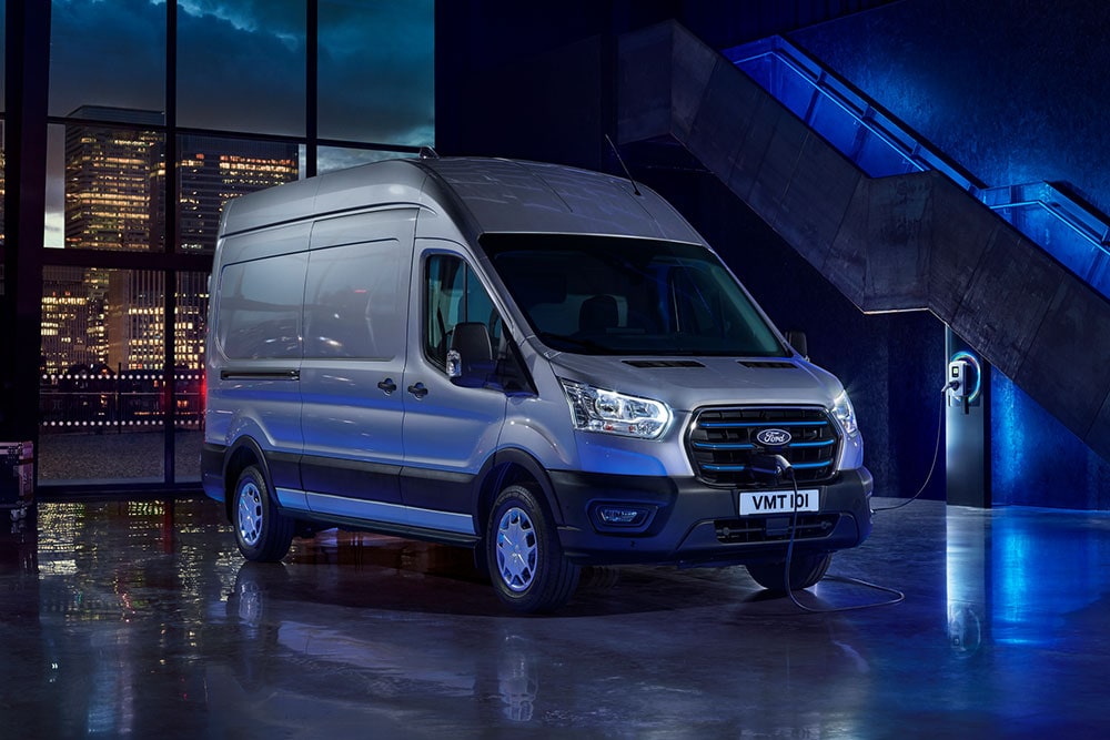 Carrinha Ford E-Transit estacionada perto de um ponto de carregamento num armazém.
