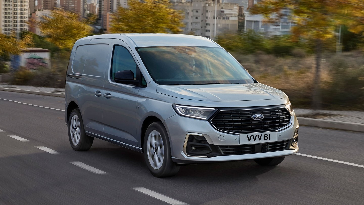 O novo Ford Transit Connect Limited em Stardust Silver conduzido numa estrada, mostrando bordos externos cromados e faróis automáticos.