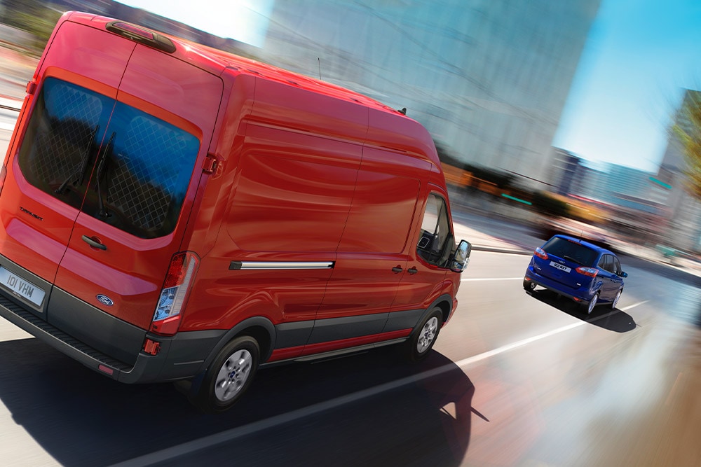 Carrinha Ford Transit vermelha a circular numa estrada urbana. 