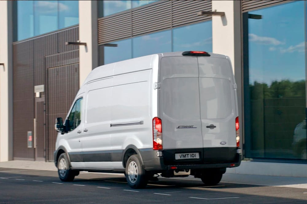 Parte traseira de uma carrinha Ford Transit prateada estacionada numa rua da cidade. 