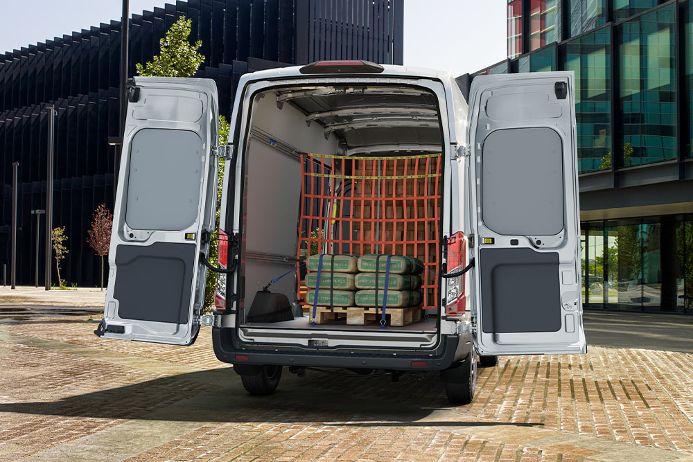 Ford Transit de cabina dupla com portas traseiras abertas, carga no interior.