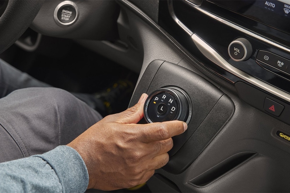 Mão a mover o seletor de mudanças rotativo na consola central da carrinha Ford Transit. 