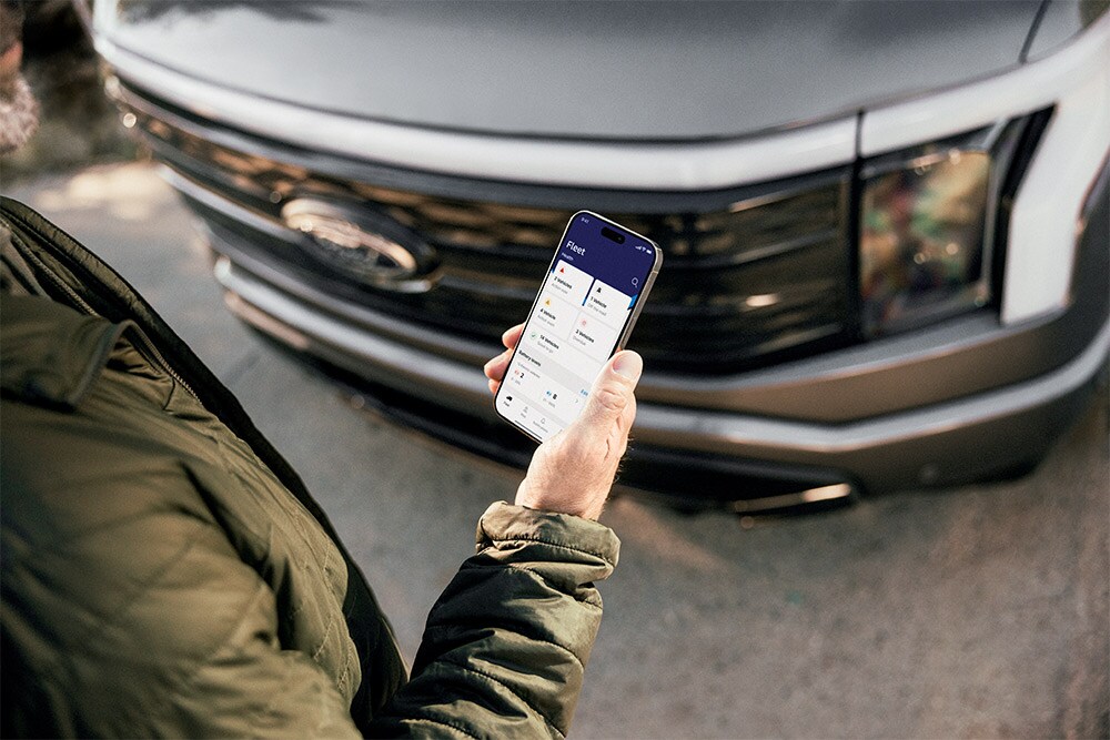 Um homem a verificar o seu smartphone em frente a uma Ford Ranger.
