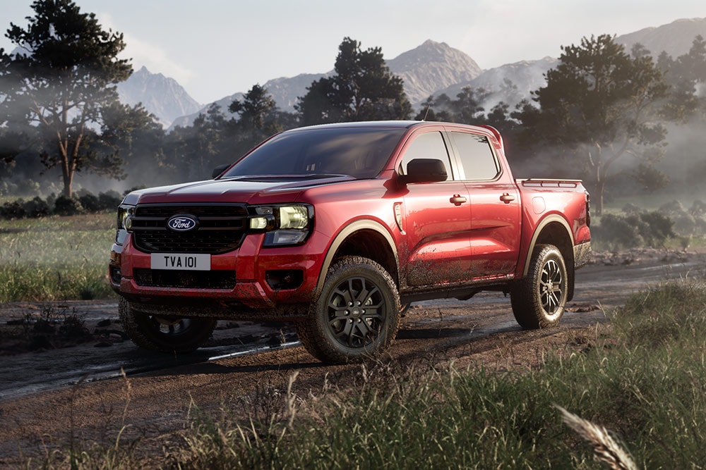 Uma Ford Ranger Raptor vermelha a circular numa estrada de terra batida no meio de uma paisagem deslumbrante.