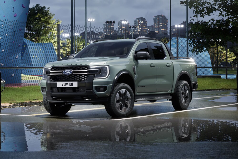 Uma Ford Ranger PHEV cinzenta estacionada em frente a uma paisagem urbana ao entardecer.