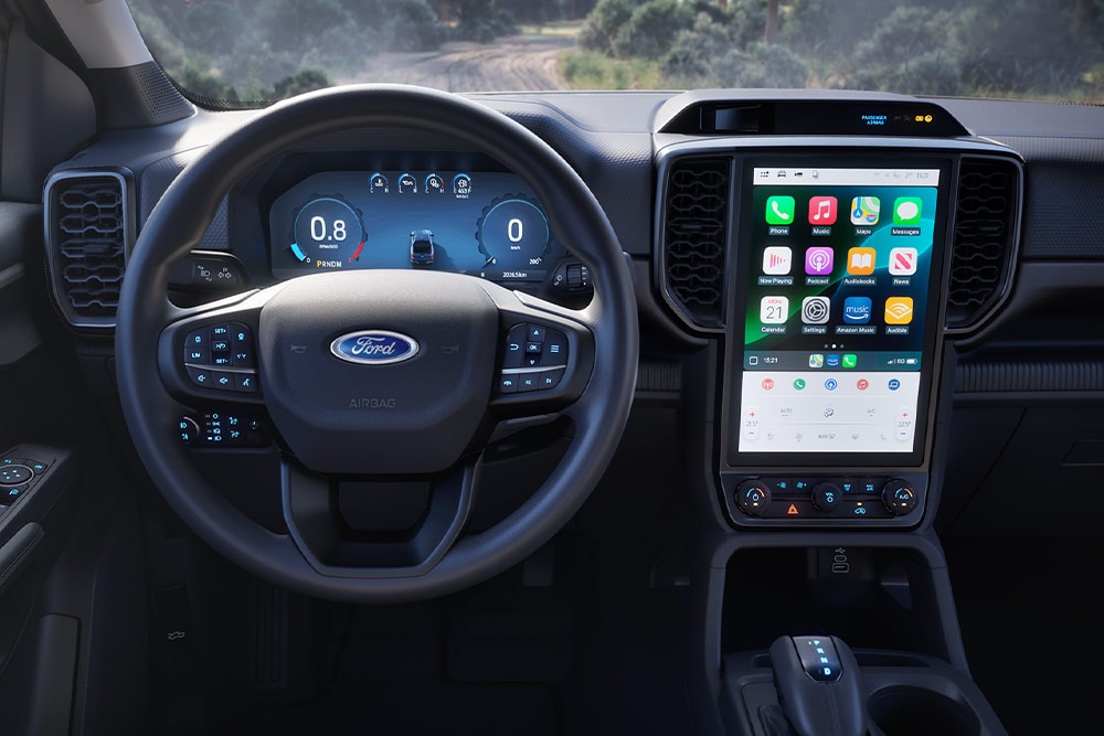 Vista interior de uma Ford Ranger Super Cab, focada no volante, nos painéis de instrumentos e no ecrã de infoentretenimento.