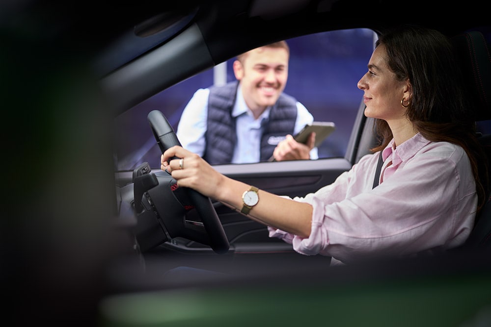 Uma pessoa no banco do condutor de um carro Ford, a olhar para um técnico que segura um tablet no lado de fora.