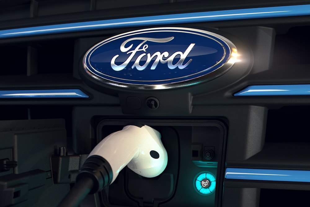 Grande plano de um cabo de carregamento branco ligado a uma porta de carregamento frontal de um veículo elétrico Ford.