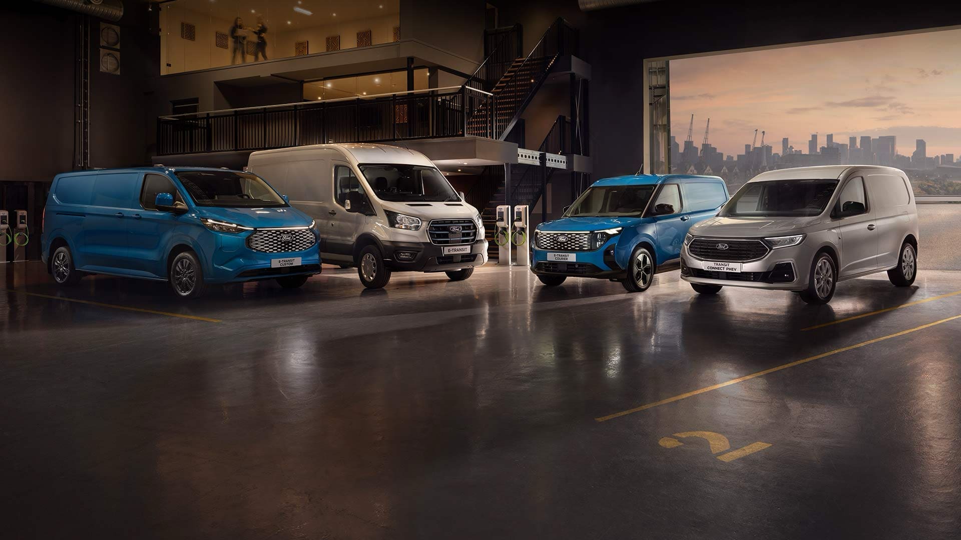 Frota de Ford Transits num showroom com o horizonte da cidade ao entardecer como pano de fundo.
