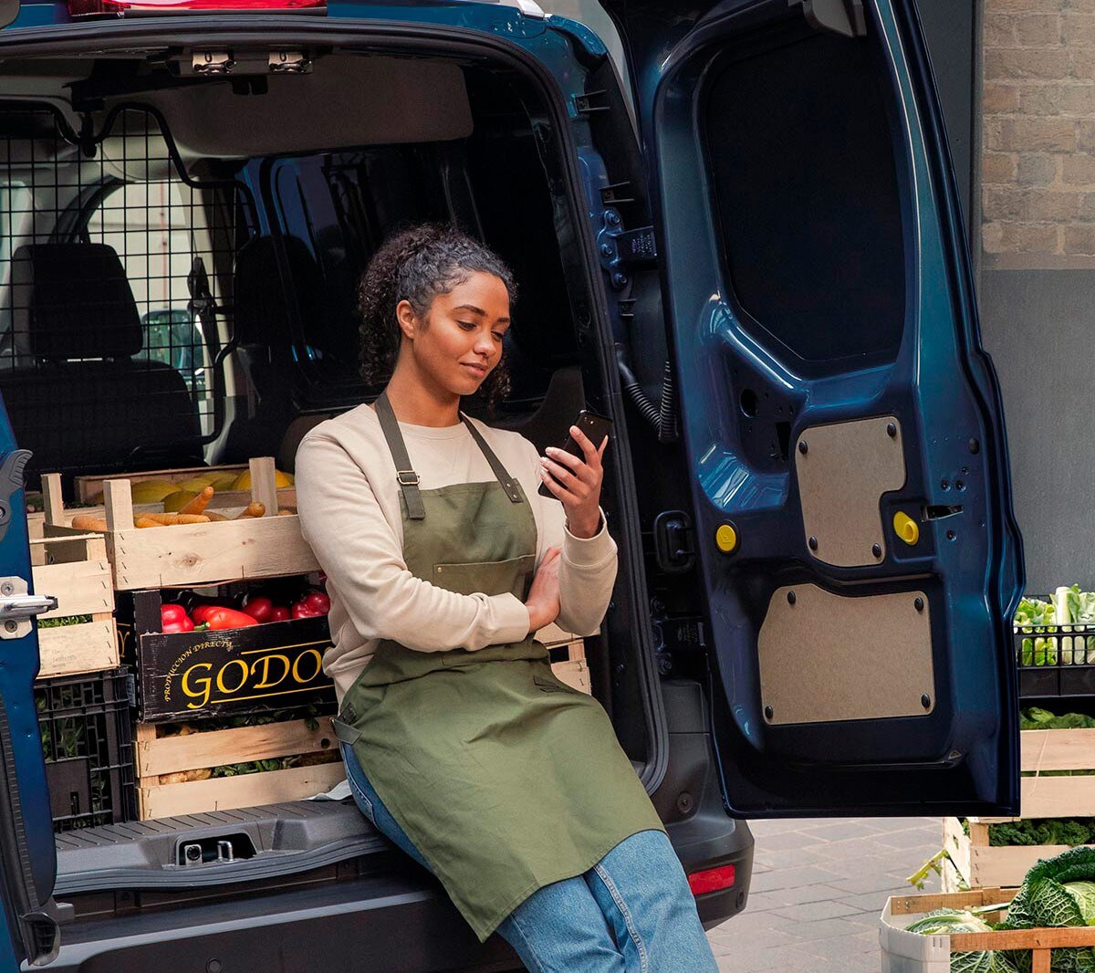 Woman with phone leaning on to a Ford Transit Courier