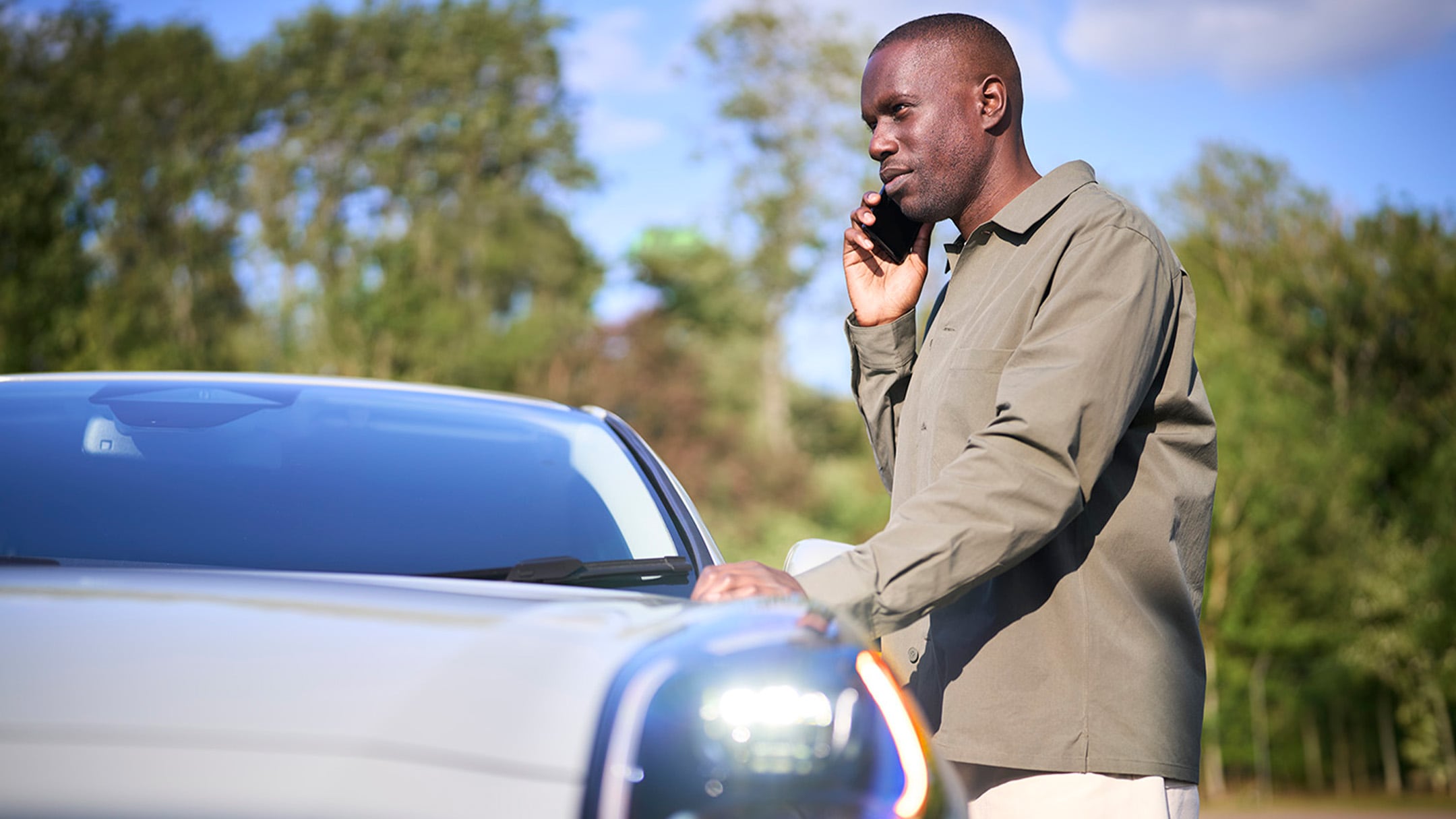 Uma pessoa coloca um triângulo de aviso vermelho junto a um carro que avariou na berma da estrada.
