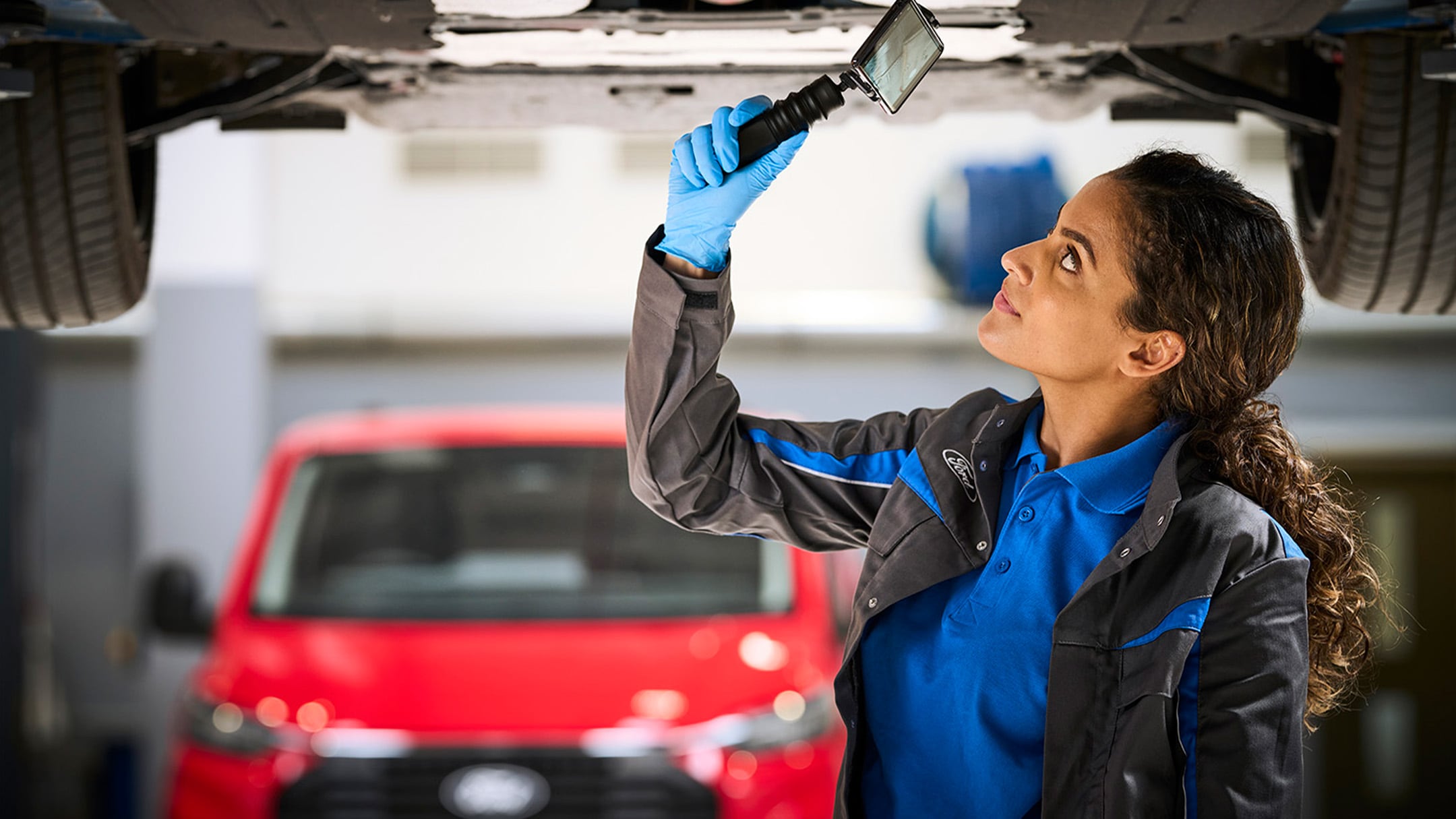 Um mecânico grava uma Verificação em Vídeo Ford num telemóvel durante uma revisão automóvel.