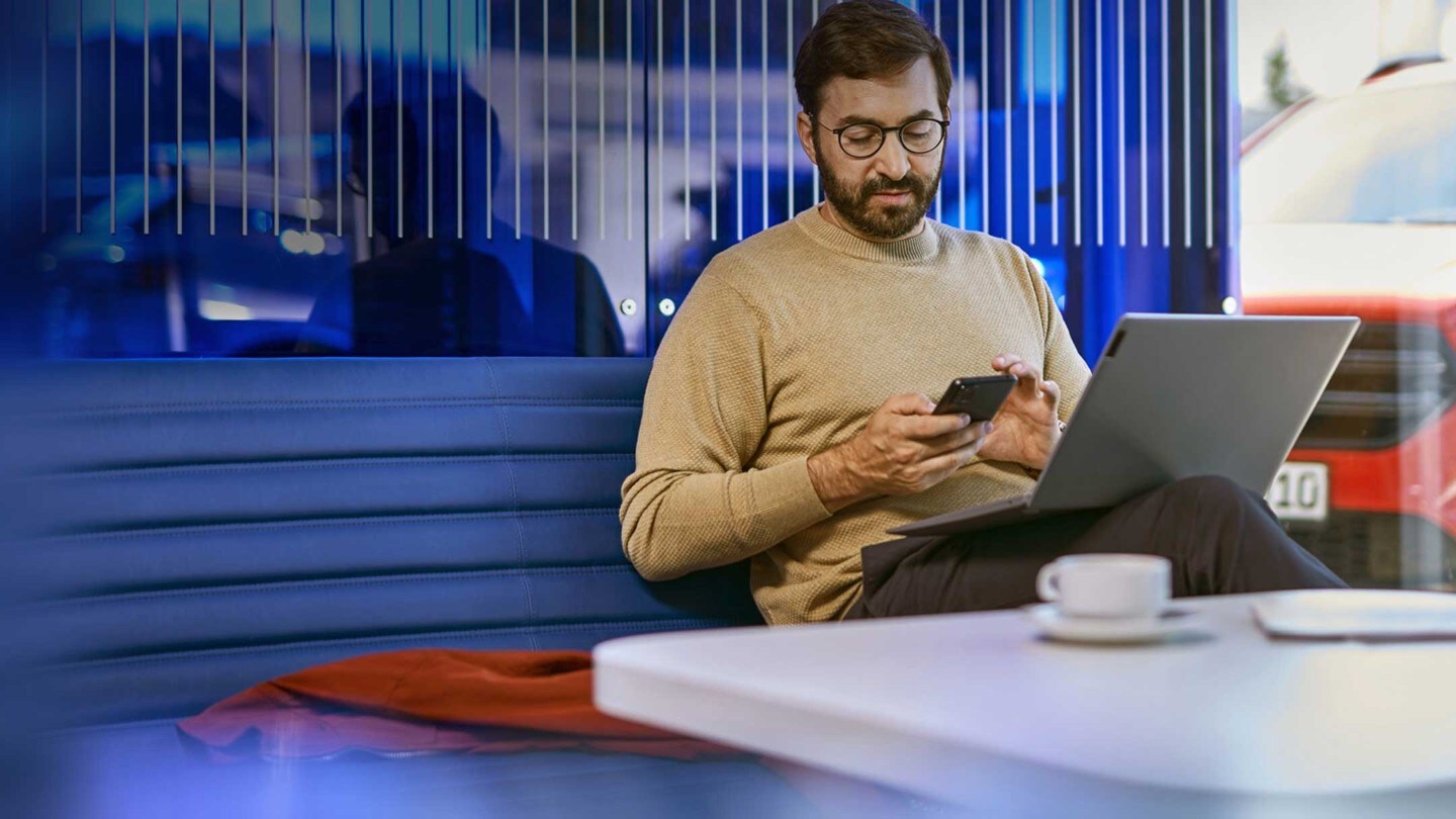 A person sitting at a desk with a laptop and a smartphone in a modern office setting.